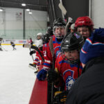 A group of athletes competing field hockey with helmet