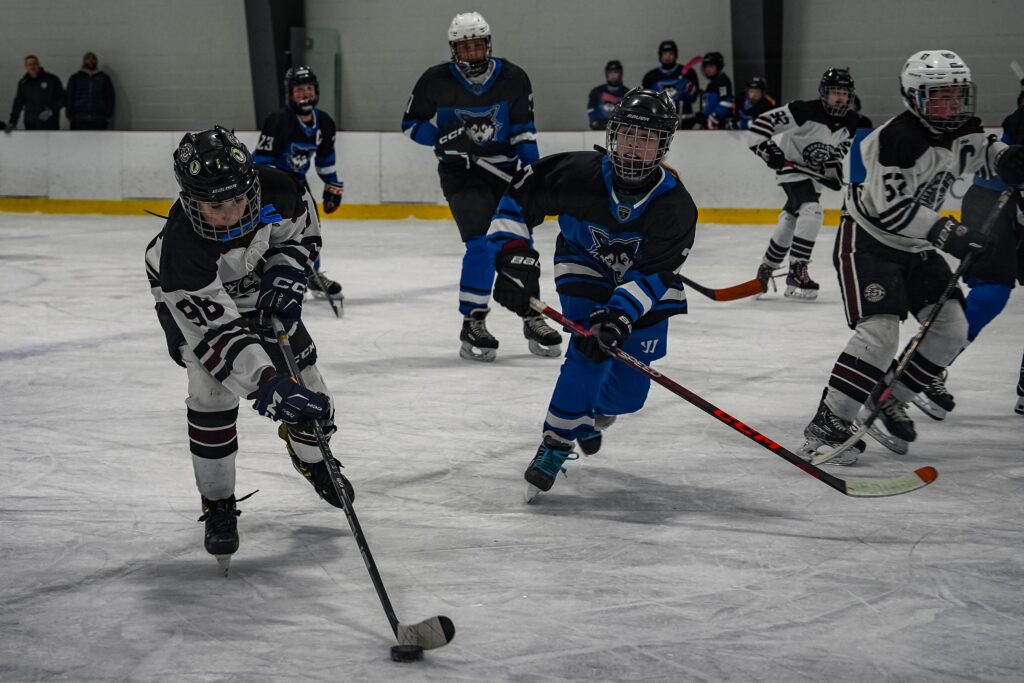 A group of athletes competing field hockey with helmet