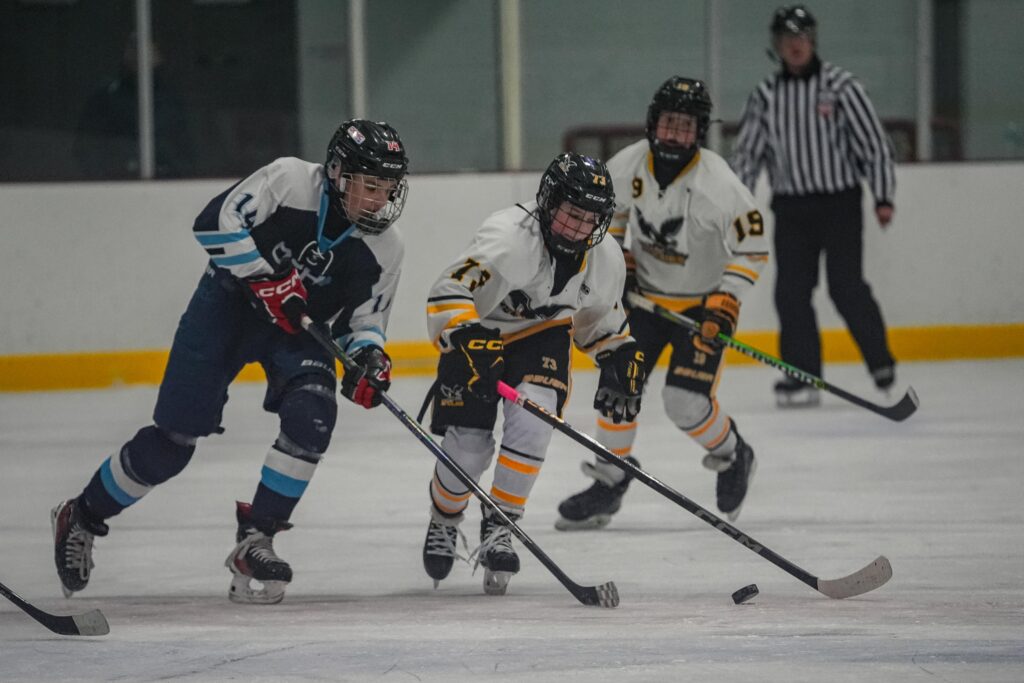 A group of athletes competing field hockey with helmet