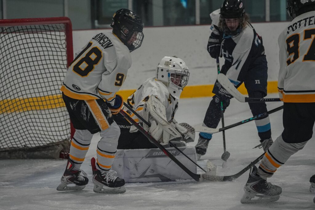 A group of athletes competing field hockey with helmet