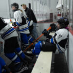 A group of athletes competing field hockey with helmet