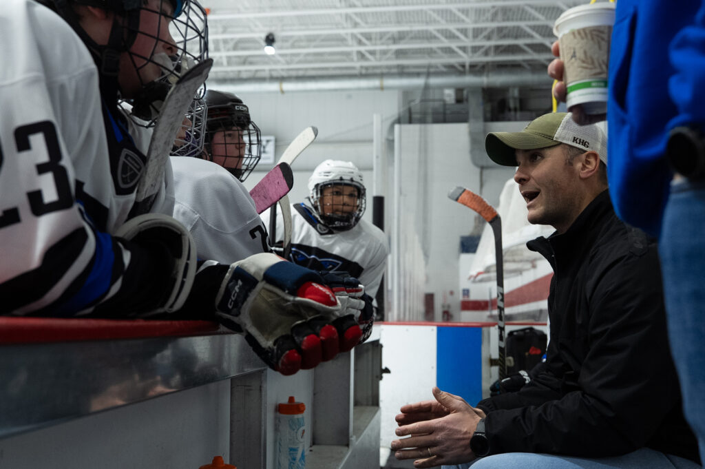 A group of athletes competing field hockey with helmet