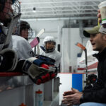 A group of athletes competing field hockey with helmet