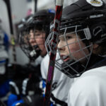 A group of athletes competing field hockey with helmet