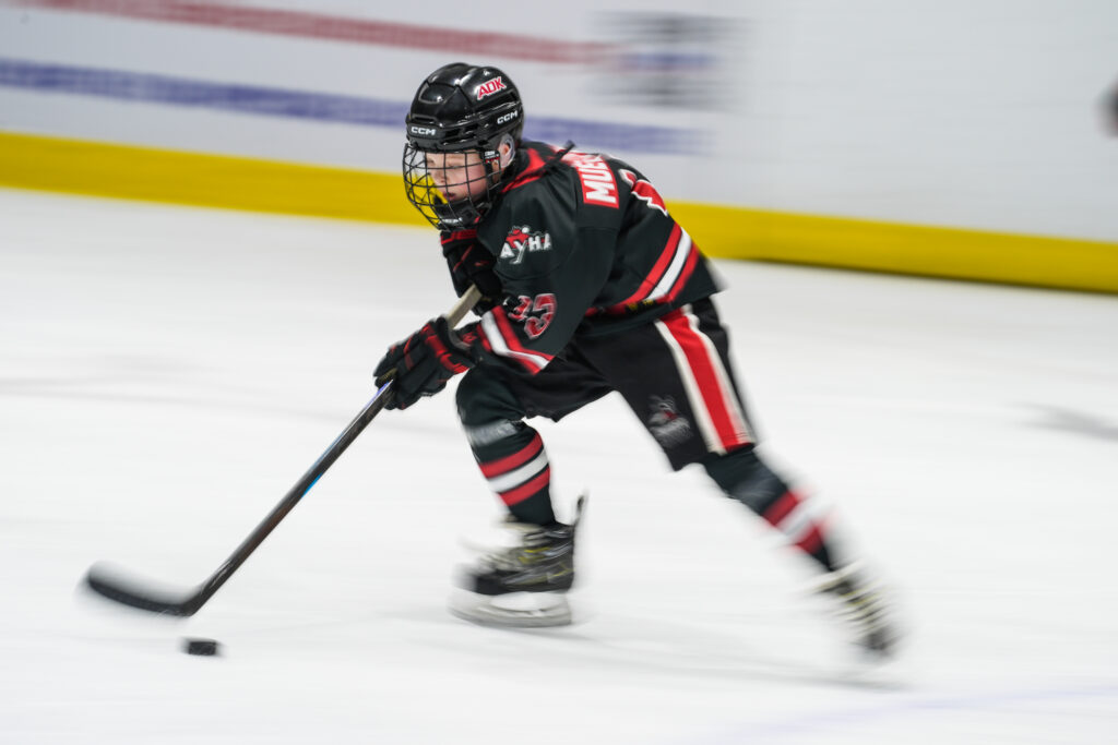 An athlete competing field hockey with helmet