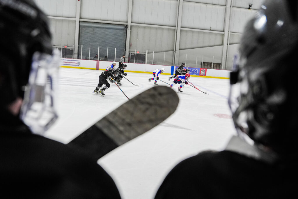 A group of athletes competing field hockey with helmet