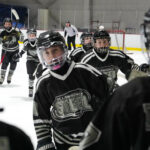 A group of athletes competing field hockey with helmet