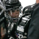 Two athletes playing football with helmet on the field