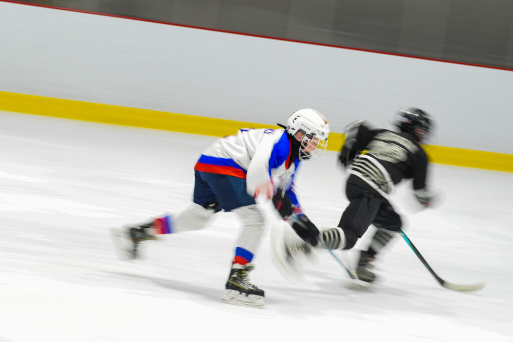 Two athletes skating with helmet on the rink