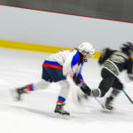 Two athletes skating with helmet on the rink