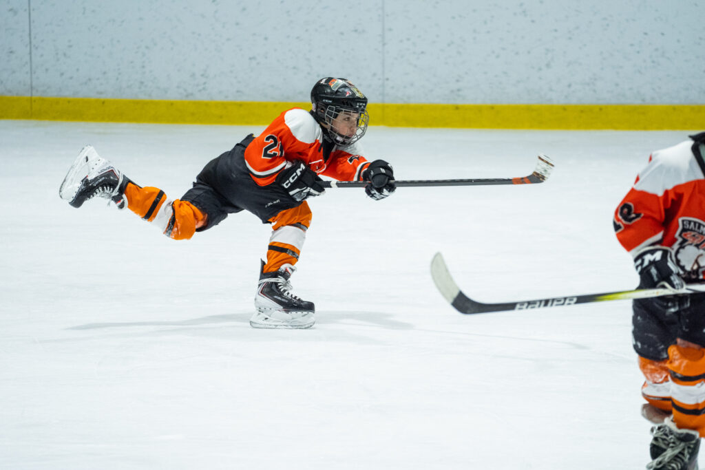 Two athletes competing field hockey with helmet