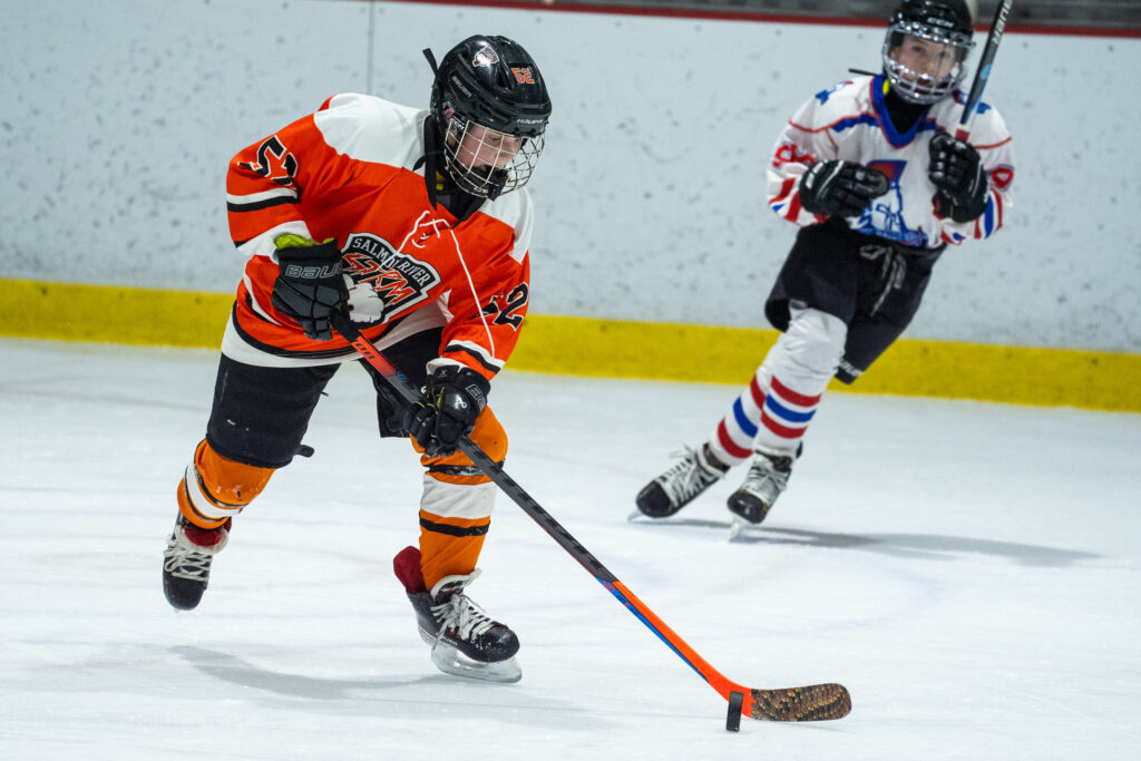 Two athletes competing field hockey with helmet
