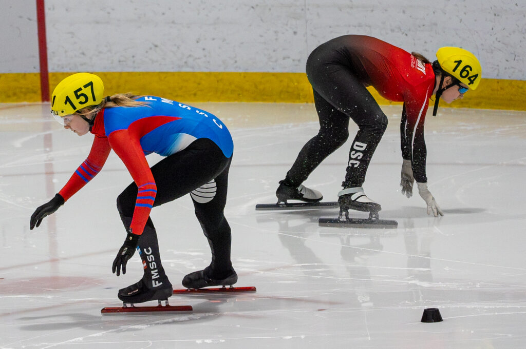 Two athletes skating with helmet on the rink