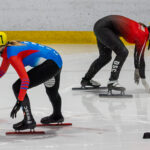 Two athletes skating with helmet on the rink