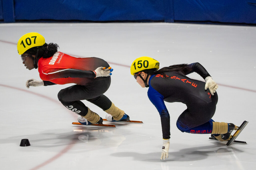 Two athletes skating with helmet on the rink