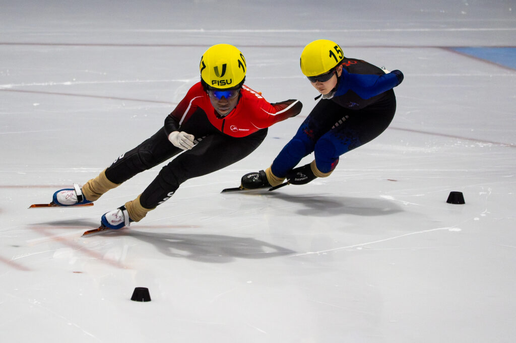 Two athletes skating with helmet on the rink