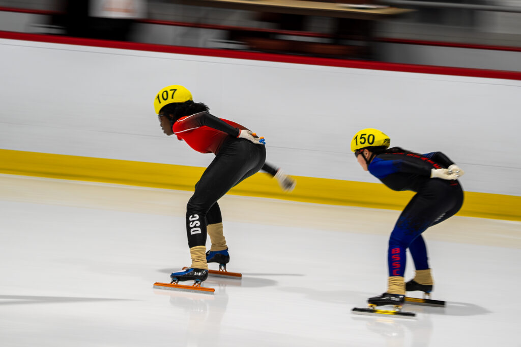 Two athletes skating with helmet on the rink