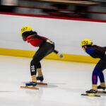 Two athletes skating with helmet on the rink