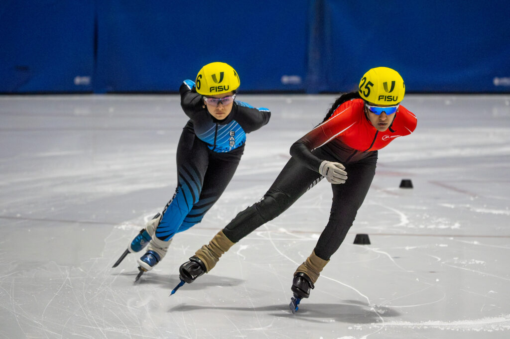 Two athletes skating with helmet on the rink