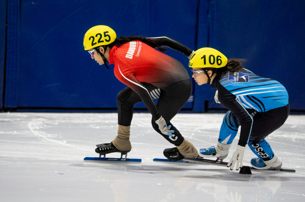 Two athletes skating with helmet on the rink