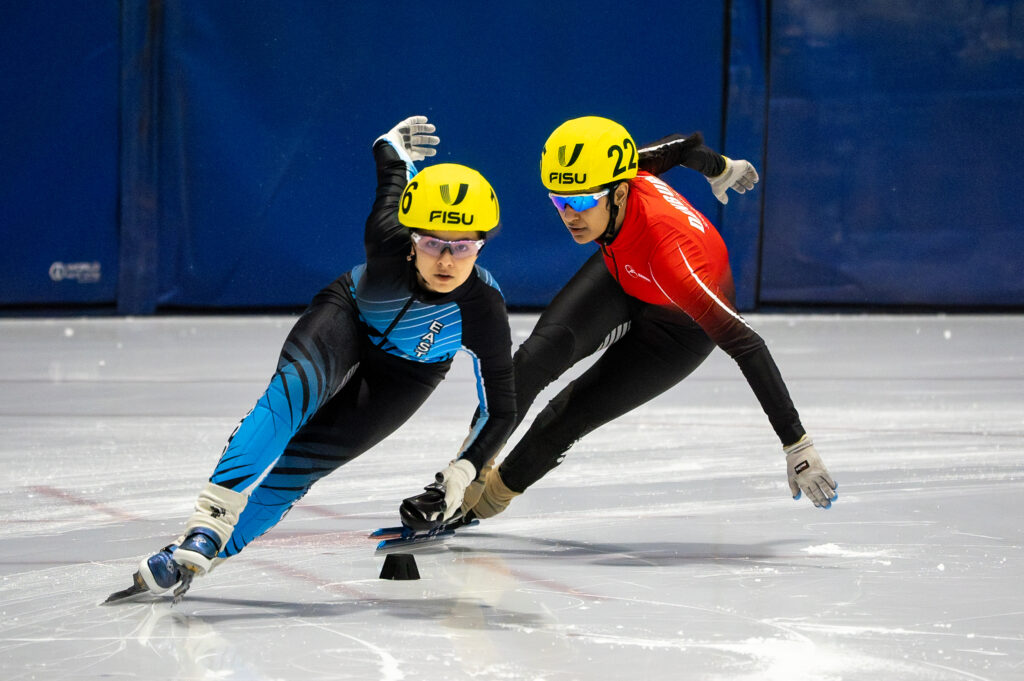 Two athletes skating with helmet on the rink