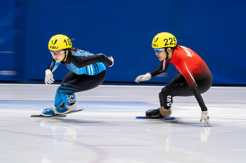 Two athletes skating with helmet on the rink