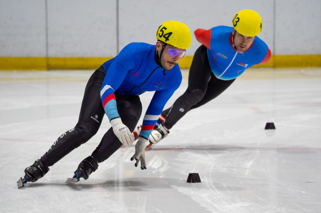 Two athletes skating with helmet on the rink