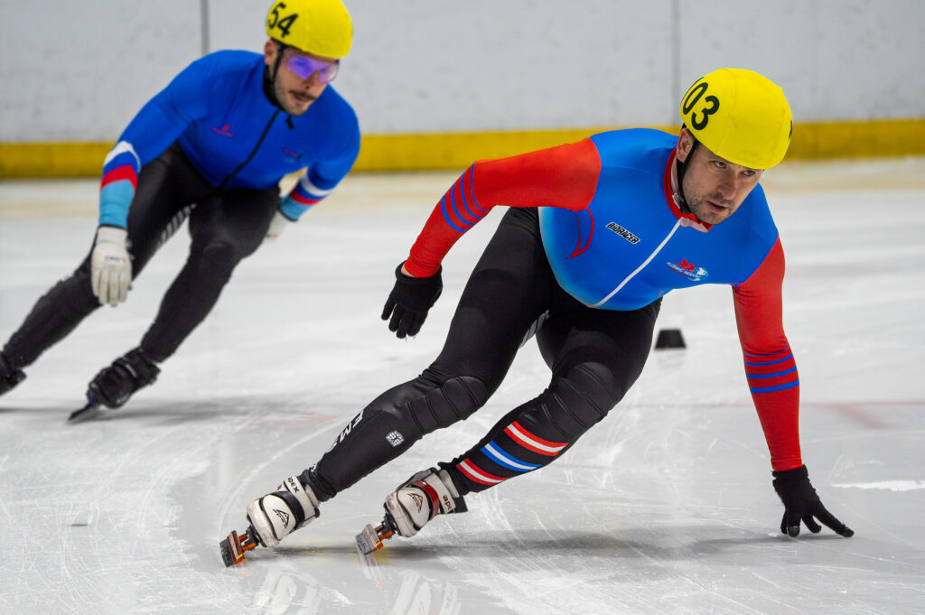 Two athletes skating with helmet on the rink