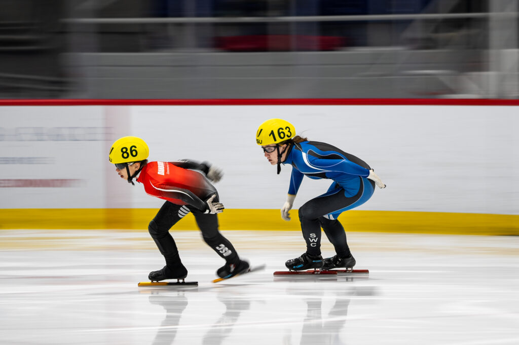 Two athletes skating with helmet on the rink