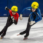 Two athletes skating with helmet on the rink