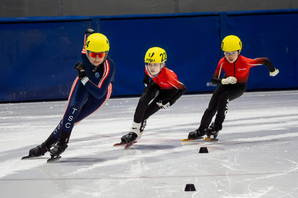 A group of athletes skating with helmet on the rink