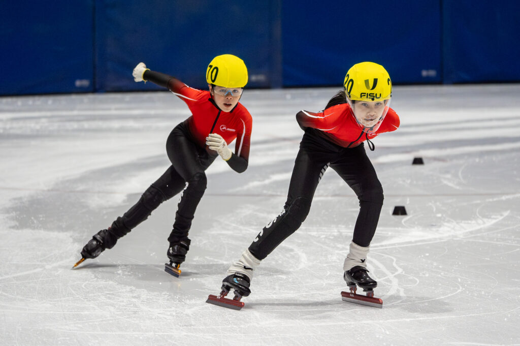 Two athletes skating with helmet on the rink